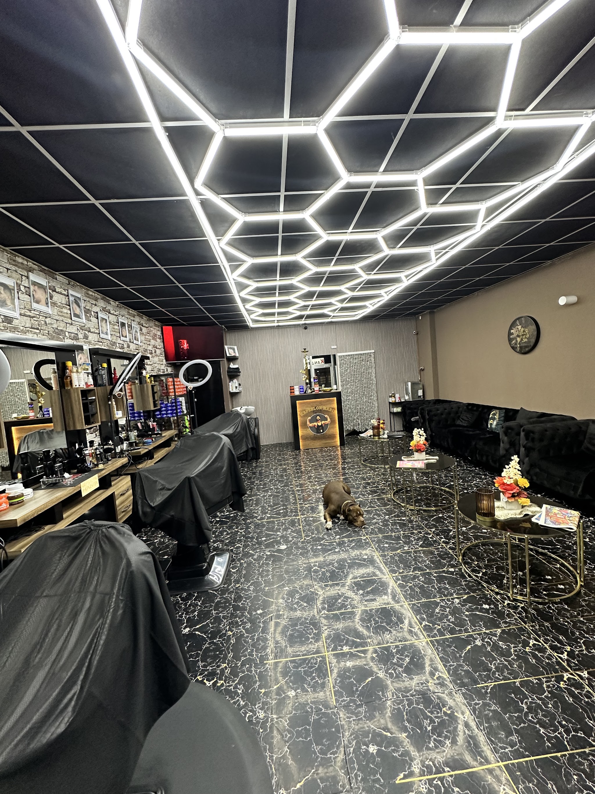 Het interieur van Kapsalon Habib met het zeshoekige lichtplafond, de zwarte marmeren vloer en de kappersstoelen