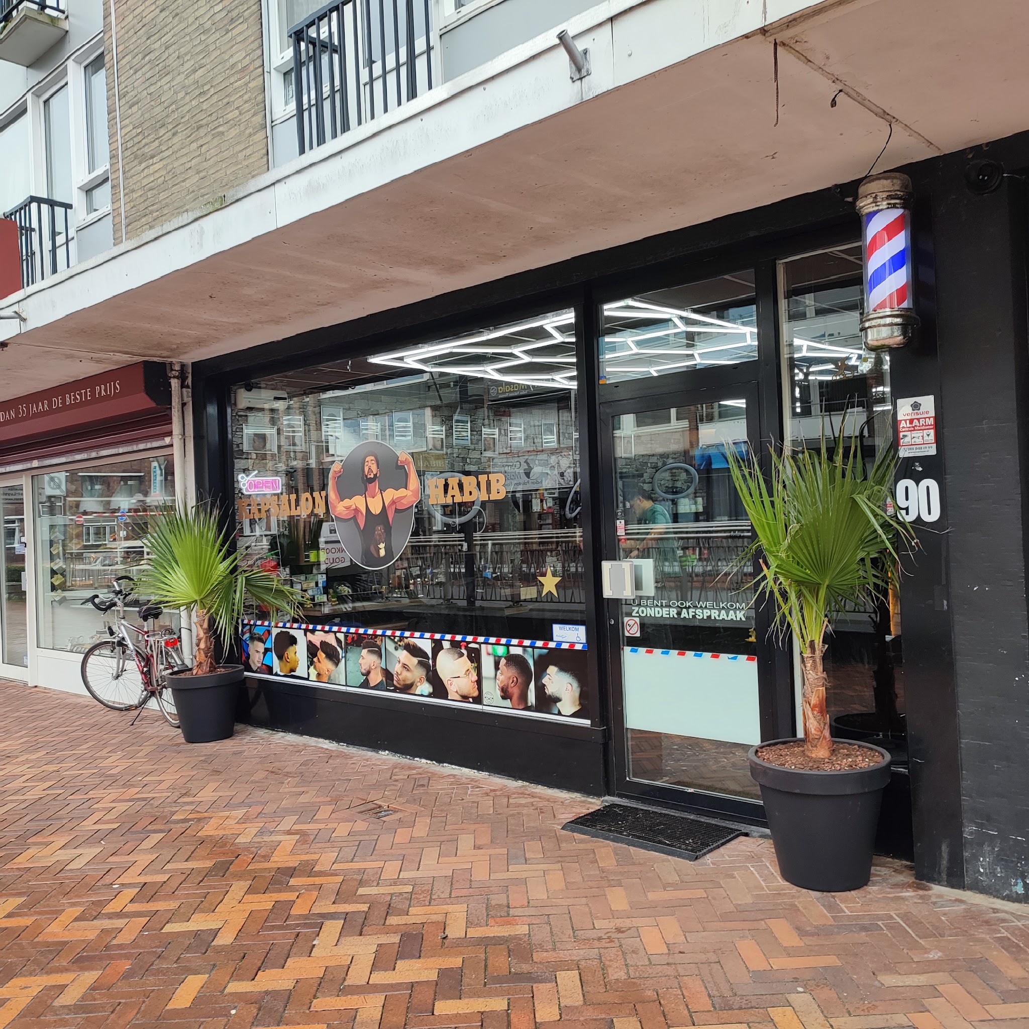 De winkelpui van Kapsalon Habib aan de Nieuwe Markt, met de barberpaal naast de deur en huisnummer 90